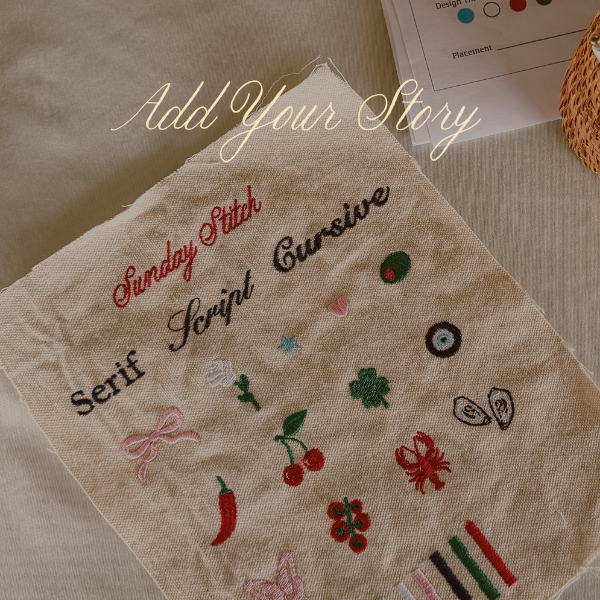 A beige linen embroidery sampler cloth with various stitched letters and small motifs, laid on a neutral fabric background. The words 'Sunday Stitch' and 'Add Your Story' are embroidered on the cloth, with a pen and a small basket partially visible in the background.