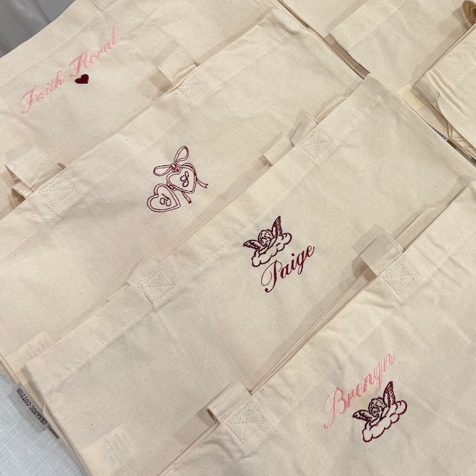 Beige pouches with embroidered designs on a white surface.